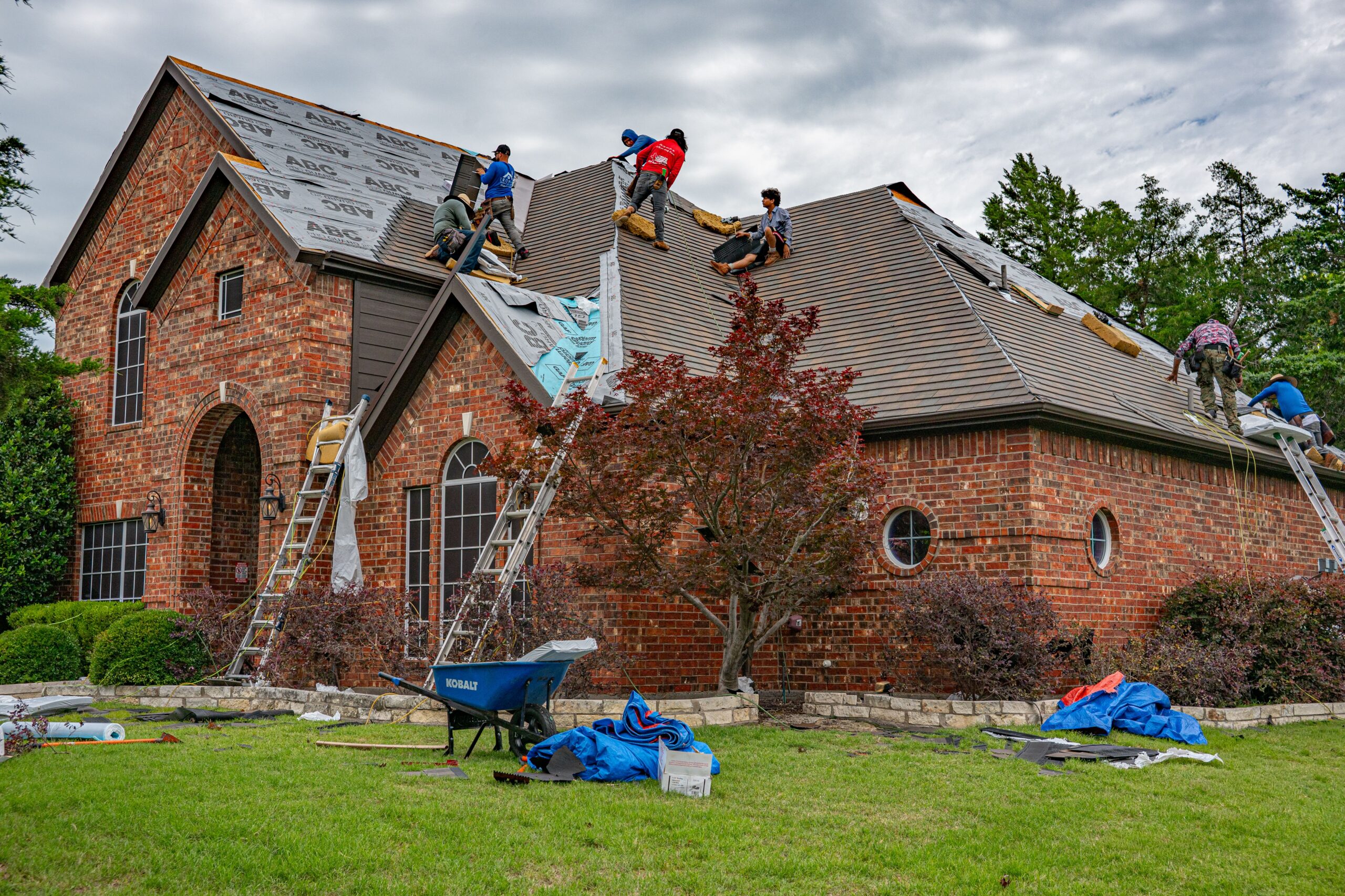 Roofing crew replacing shingles on a home's roof, the exterior work a general contractor in the Twin Cities manages.