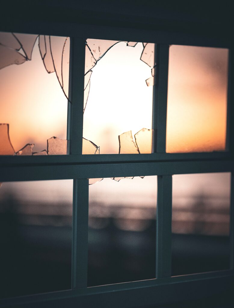 Cracked and broken glass in a window pane after a storm, the kind of storm damage window repair Lakeside Roofing & Remodeling handles across the Twin Cities.