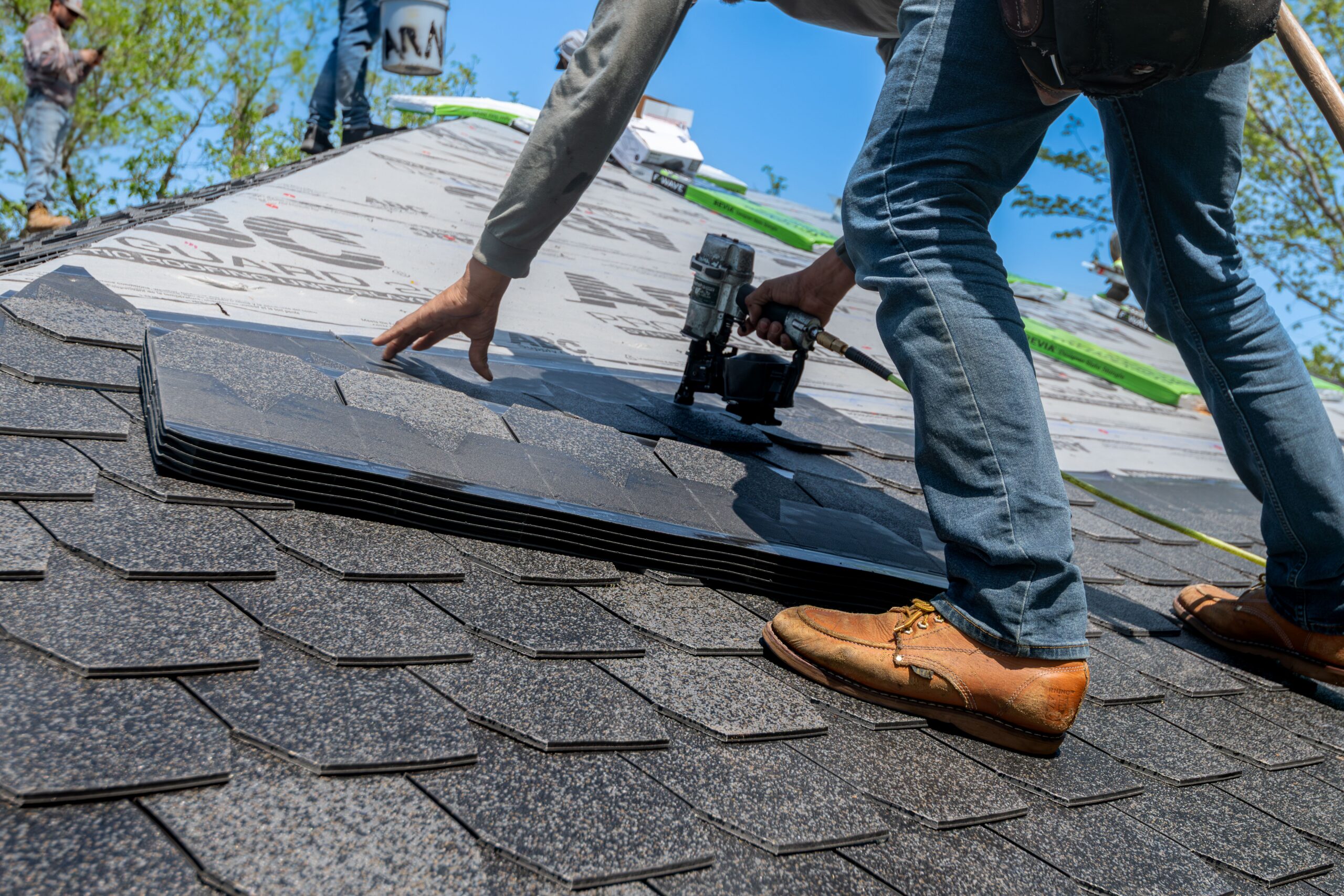 A roofer nails down new asphalt shingles during a Twin Cities roofing job by Lakeside Roofing & Remodeling.