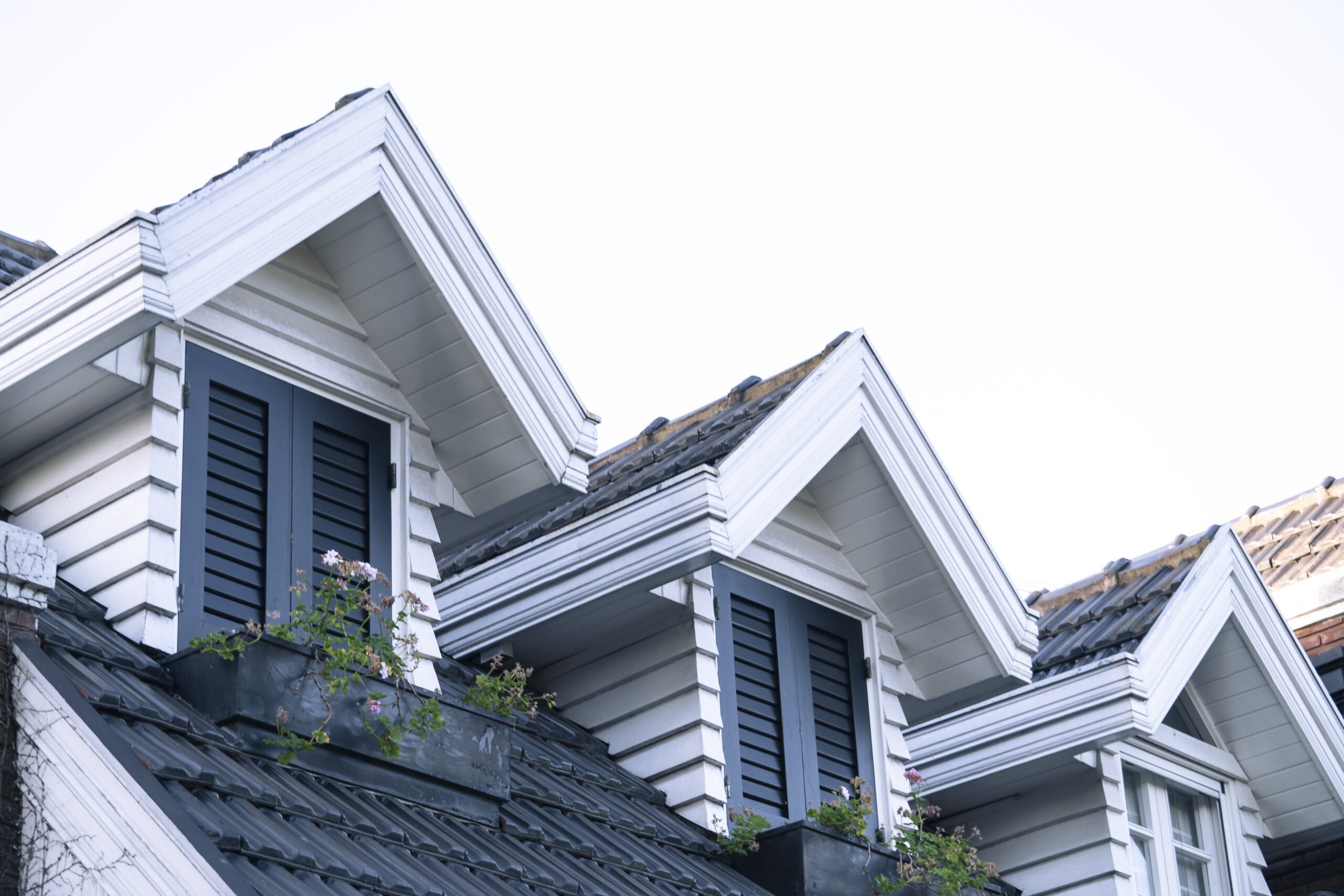 White dormer windows with dark shutters on a Twin Cities home, the kind of window replacement Lakeside Roofing & Remodeling handles.